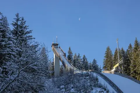 Skisprungschanze Langenwaldschanze Schonach im Winter mit Schnee und Wald, Mond am blauen Himmel