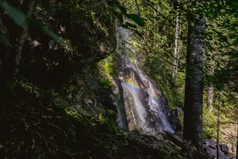 Zweribachwasserfall stürzt über moosige Felsen, im Sprühnebel ein kleiner Regenbogen, umgeben von Schwarzwaldwald