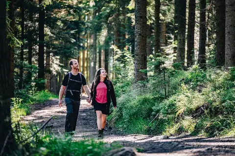 Paar wandert Hand in Hand auf einem Waldweg im Schwarzwald