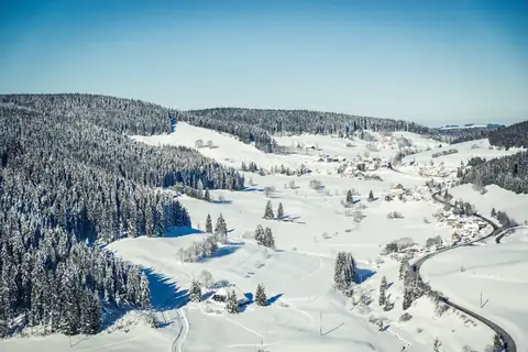 Verschneites Schwarzwaldtal mit Streusiedlung, Wäldern und kurviger Strasse, kein Turm sichtbar