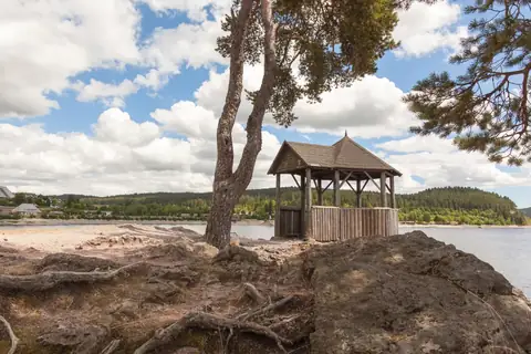 Hölzerner Pavillon am felsigen Seeufer unter Kiefern am Schluchsee
