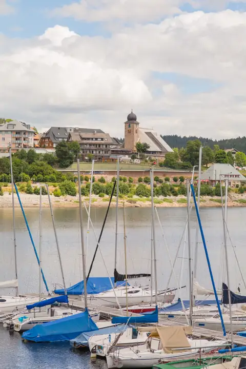 Segelboote im Hafen von Schluchsee mit Blick auf Ortskirche und Uferpromenade