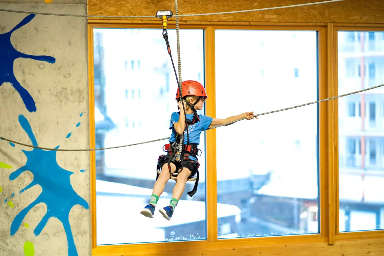 Ein Kind rutscht auf einer Seilrutsche im Indoor Hochseilgarten in der Indoor Spiel- & Sporthalle Fundorena