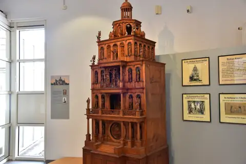 Mehrstöckiges Holzmodell einer historischen Kunstuhr mit Figuren in einem Museumsraum