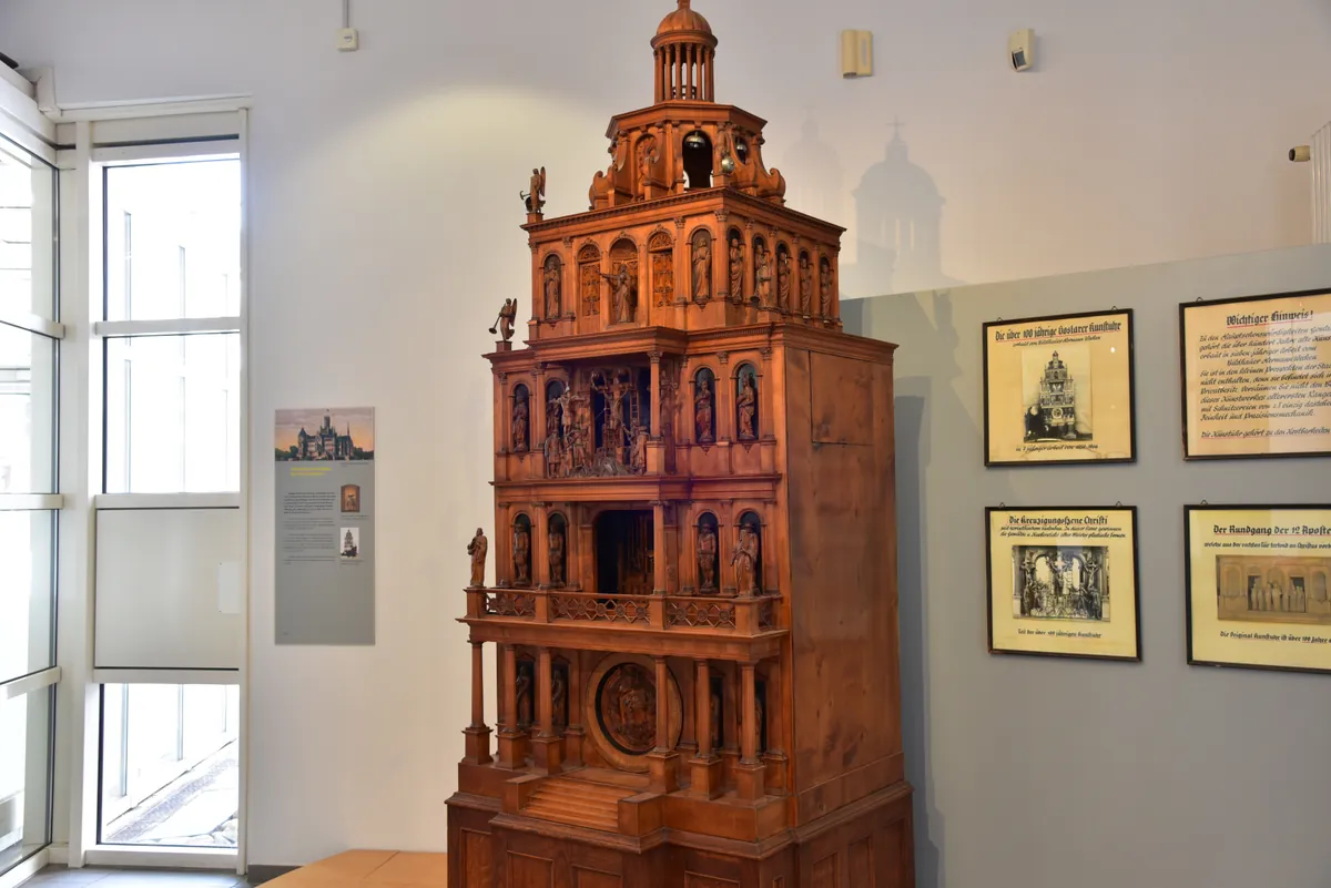 Mehrstöckiges Holzmodell einer historischen Kunstuhr mit Figuren in einem Museumsraum