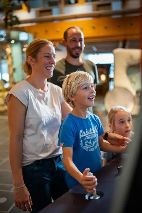 Familie mit zwei Kindern am Empfangstresen eines naturkundlichen Museums, lächelnd