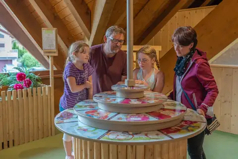 Familie mit zwei Mädchen erkundet interaktive Drehtisch-Ausstellung im Schwarzwaldhaus der Sinne