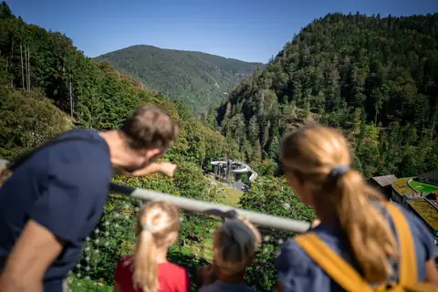 Familie blickt von Aussichtsplattform auf Tal mit Rodelbahn und Schwarzwaldpanorama