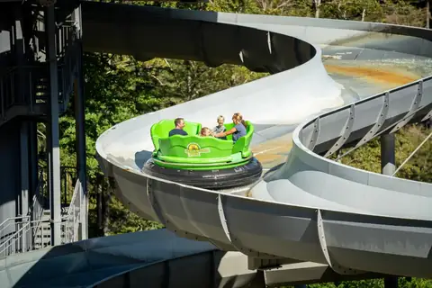 Familie in grünem Rundboot auf der Wasserbahn im Steinwasen Park, Schwarzwald