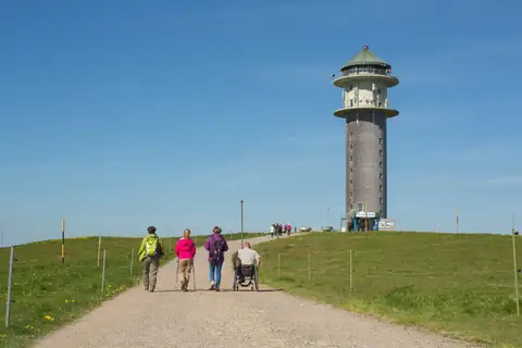 Wanderer und Rollstuhlfahrer auf dem Weg zum Feldbergturm auf dem Feldberg im Schwarzwald