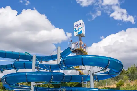 Blaue Wasserrutsche des Aqua Fun Schluchsee mit Logo-Turm vor blauem Sommerhimmel