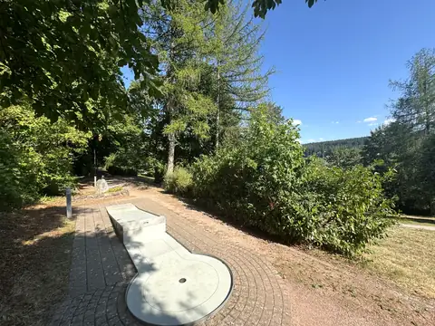 Minigolfbahn am Waldrand in St. Georgen, dahinter der Blick über bewaldete Schwarzwaldhöhen