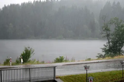 Windgfällweiher im Starkregen, Blick über das regenverhangene Wasser zum Nadelwald
