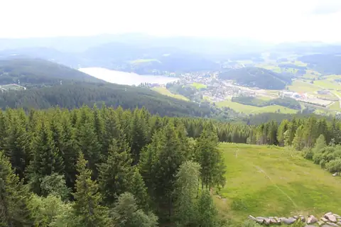 Aussicht vom Hochfirstturm auf den Titisee mit Ortschaft, umgeben von bewaldeten Hügeln