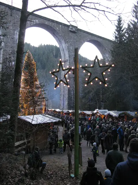 Weihnachtsmarkt unter dem Ravennaviadukt mit beleuchtetem Baum und Lichterstern