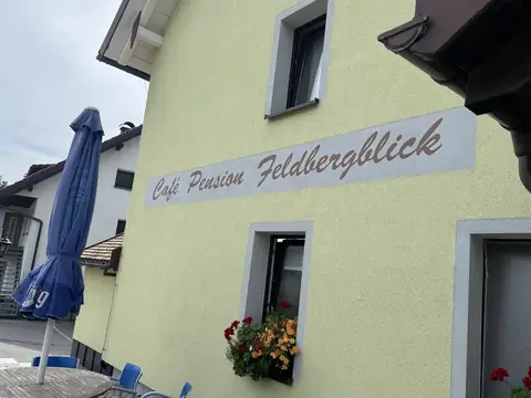 Hausfassade mit dem Schriftzug Café Pension Feldbergblick und Blumenkasten am Fenster