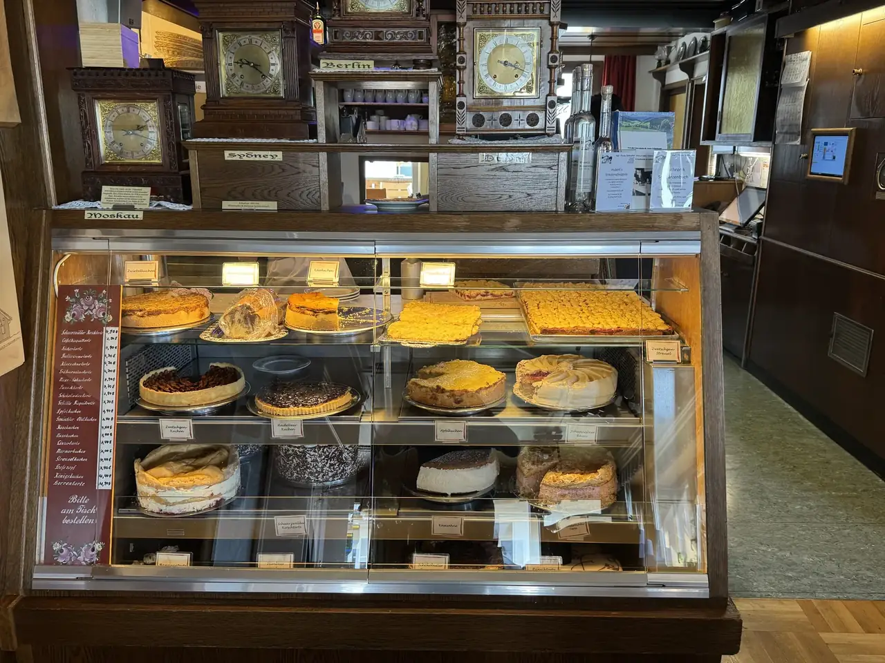 Kuchentheke im Café Feldbergblick mit Torten und Blechkuchen, darüber alte Uhren