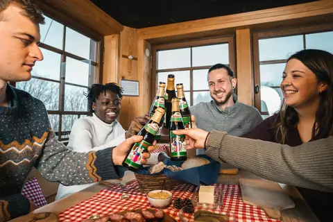 Gäste stoßen mit Rothaus Tannenzäpfle in der gemütlichen Stube des Ochsenhofs an
