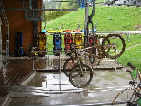 Mountainbike hängt an Sessellift-Haken, dahinter bunte Schlitten in Liftstation Todtnau