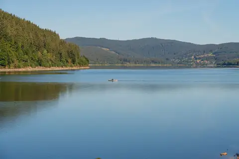 Schluchsee mit spiegelnder Wasseroberfläche, ein Kajak auf dem See, Schwarzwald-Berge im Hintergrund