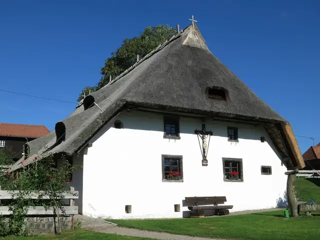 Reetgedecktes Schwarzwaldhaus mit weißer Fassade und Kruzifix, Klausenhof Herrischried
