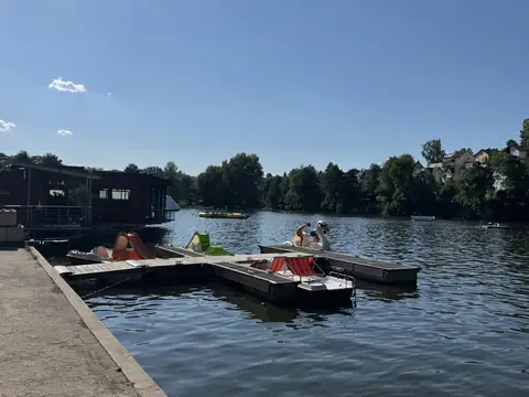 Holzsteg am Klosterweiher mit bunten Tretbooten, links das Seehaus am Ufer