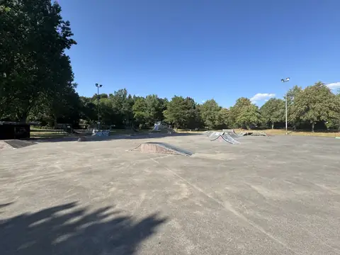 Betonierter Skatepark mit Rampen direkt am Klosterweiher, dahinter Bäume und Spielgeräte